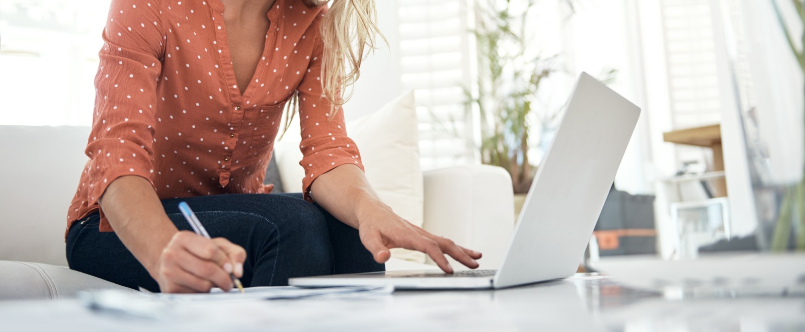 a woman sitting on a couch working on her laptop computer