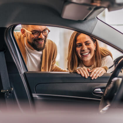 Two adults looking inside a new car