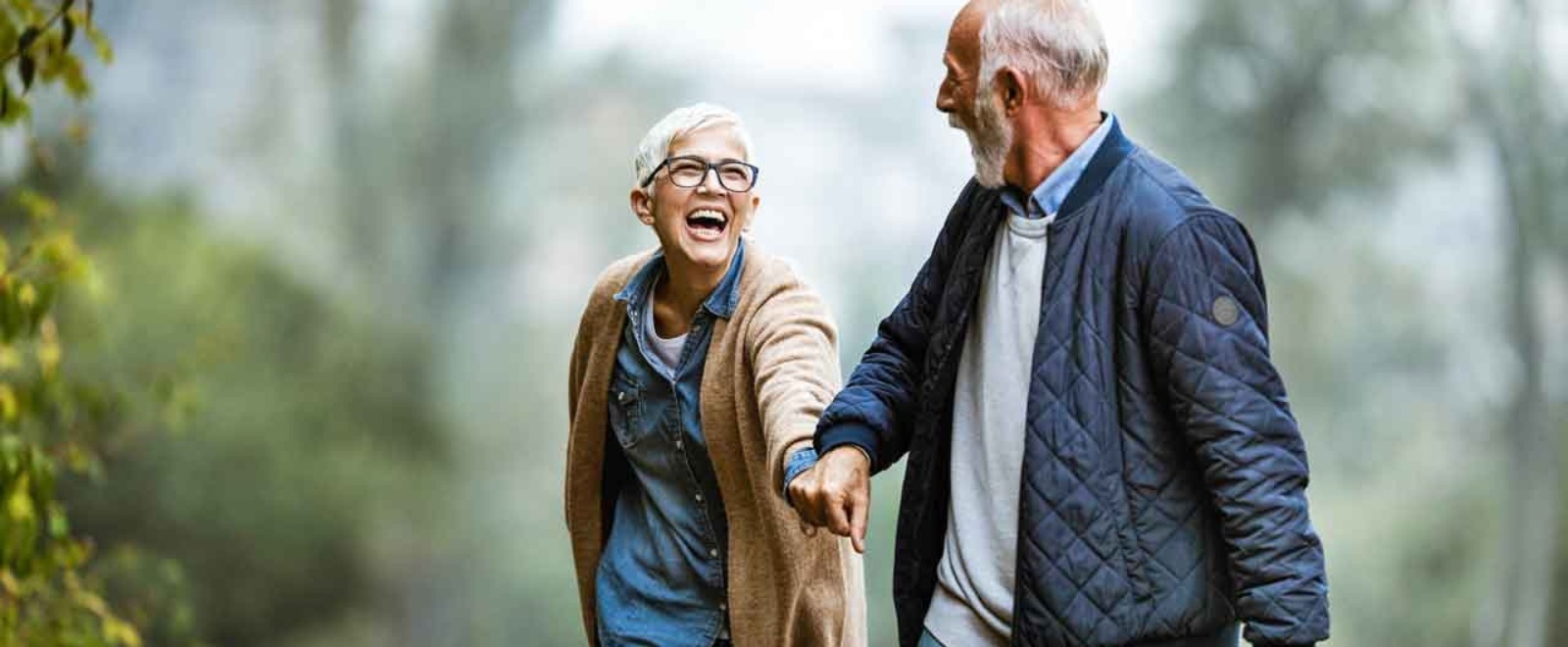 an elder couple holding hands and laughing